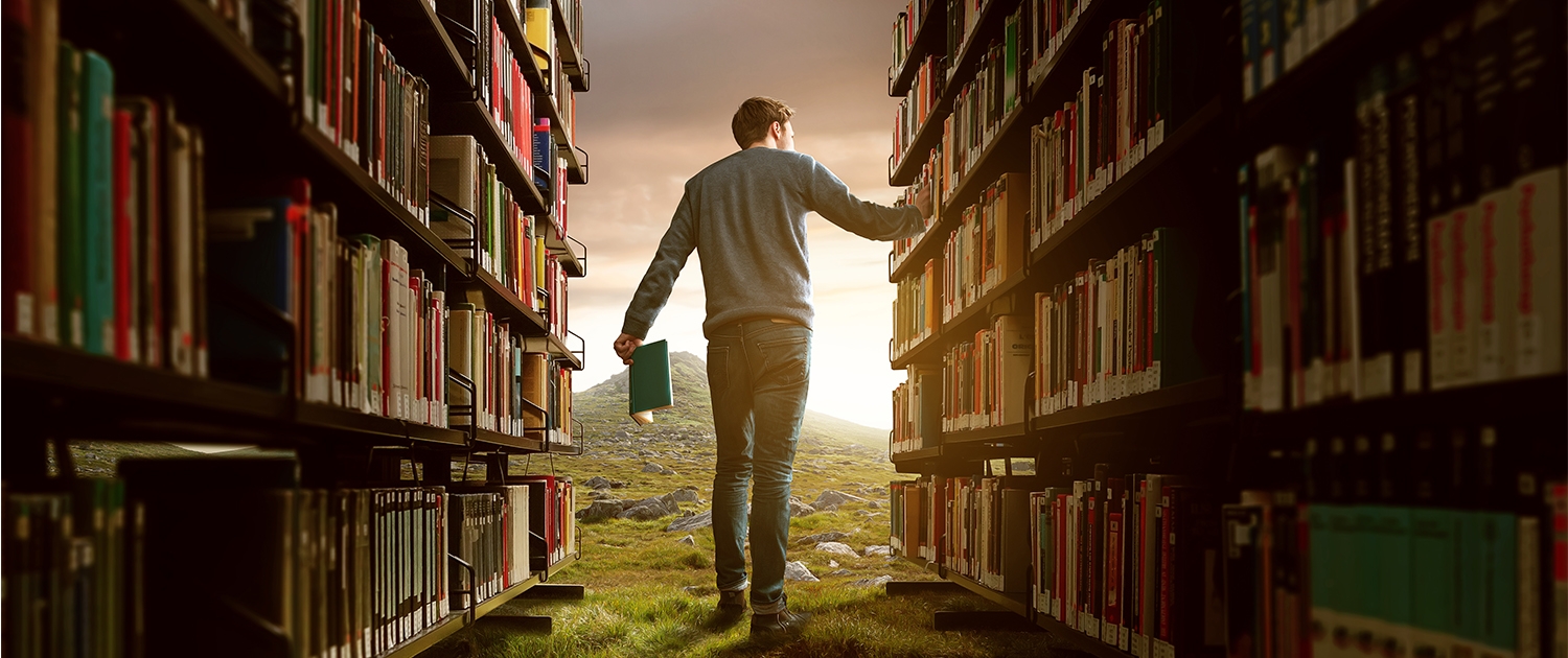 Ein Man zwischen zwei Bücheregalen in der Wildnis.