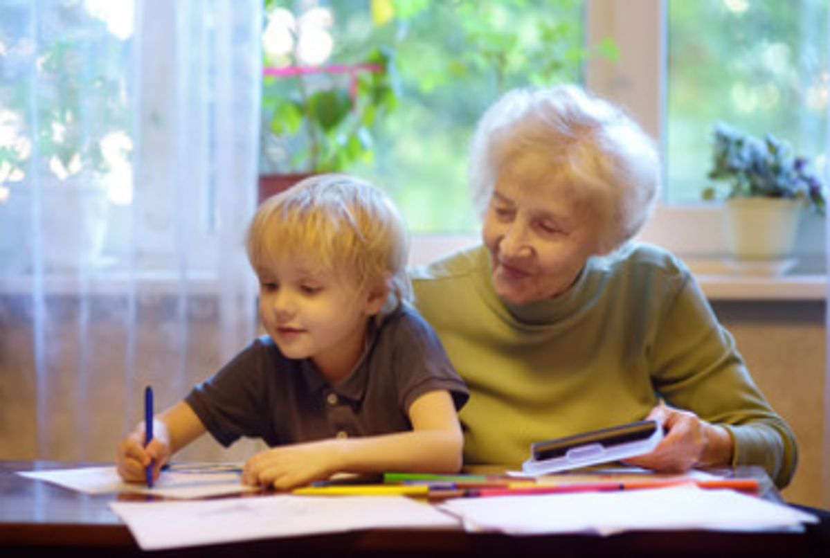 Eine Ältere Frau hilft einem Kind bei den Hausaufgaben.