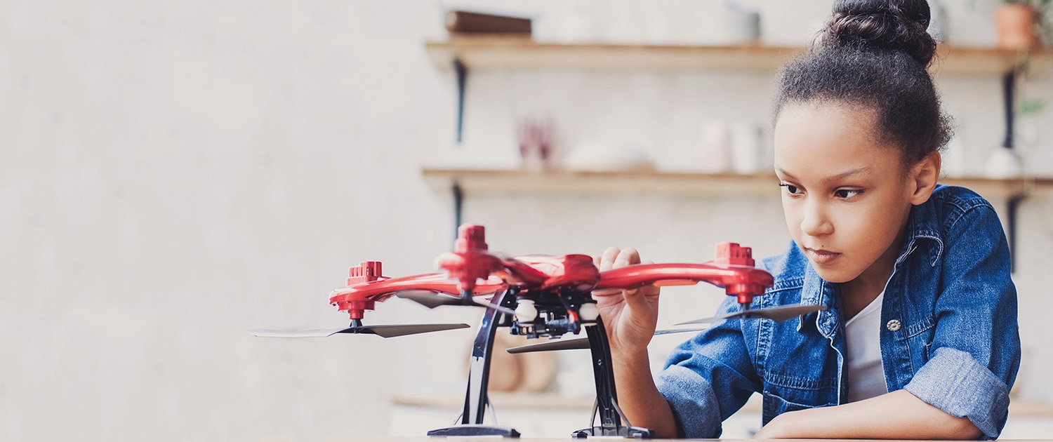 Ein Mädchen hält eine Drohne in der Hand.