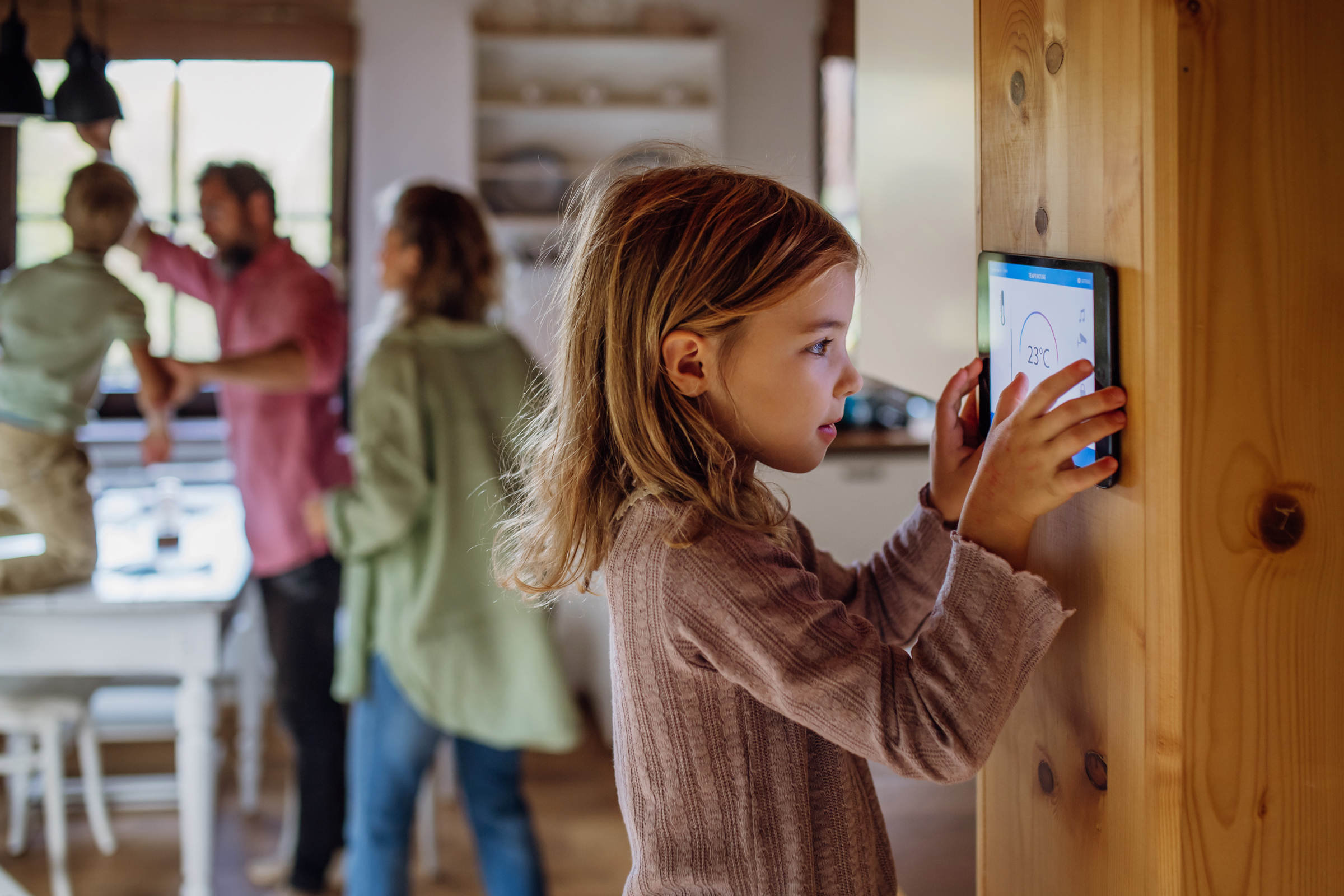 Girl looking at smart thermostat at home, checking heating temperature. Concept of sustainable, efficient, and smart technology in home heating and thermostats. Girl looking at smart thermostat at home, checking heating temperature. Concept of sustainable, efficient, and smart technology in home heating and thermostats.