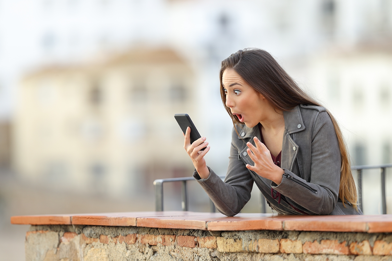 Surprised woman using a smart phone in a terrace Surprised woman using a smart phone in a terrace