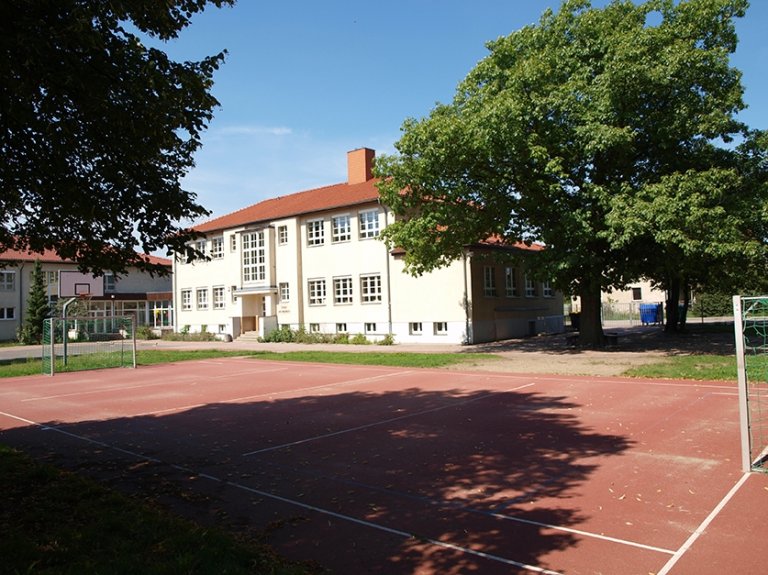 Ein Pausenhoff mit einem Fußballplatz und gleichzeitig basketballplatz von der allgemeinen Förderschule Am Waldblick in Mahlow.                  Im Hintergrund das Schulgebäude.