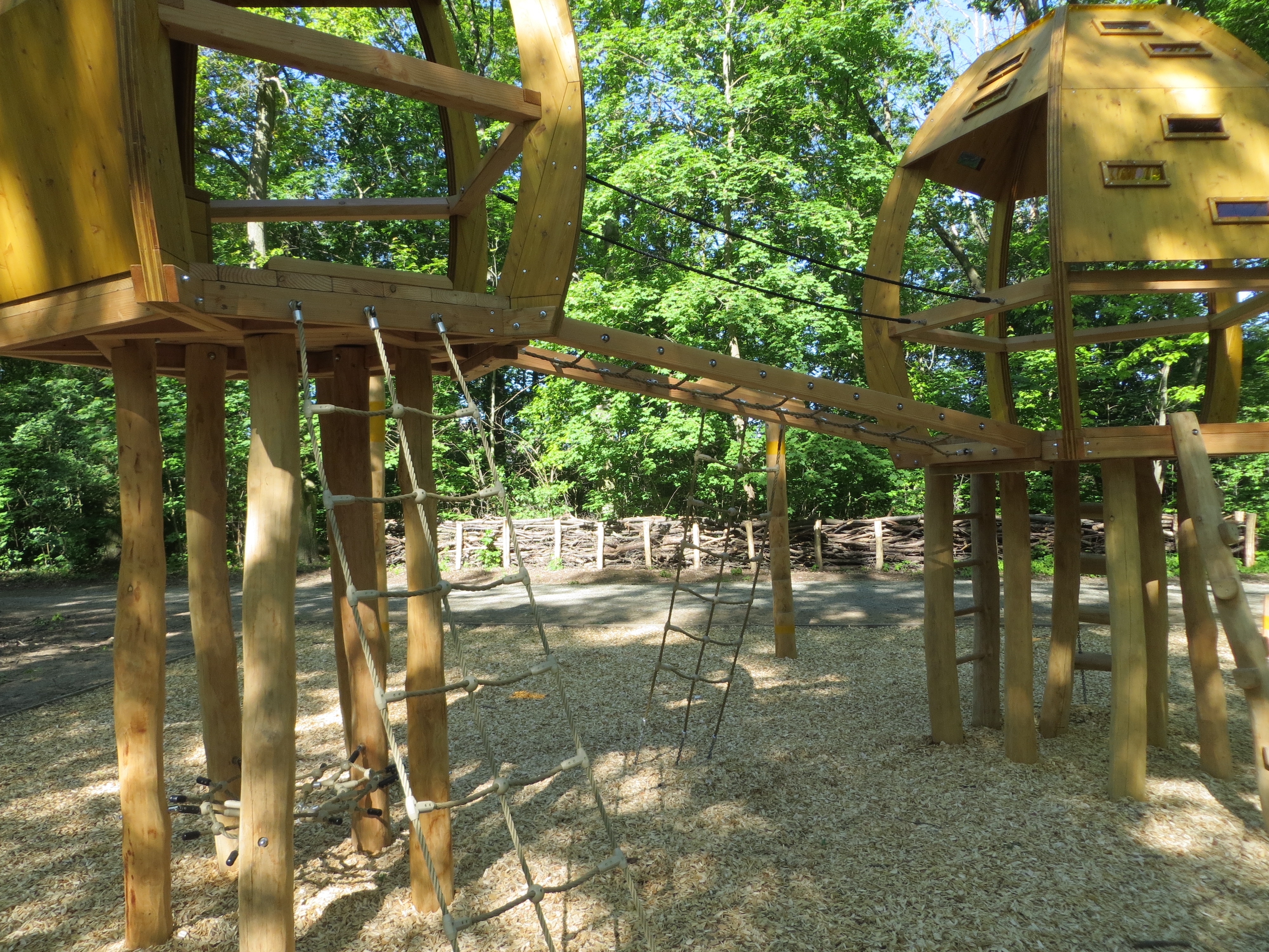 Spielbauten aus Holz darunter zwei Hütten auf Stelzen die mit Seilen und Strickleitern verbunden sind.